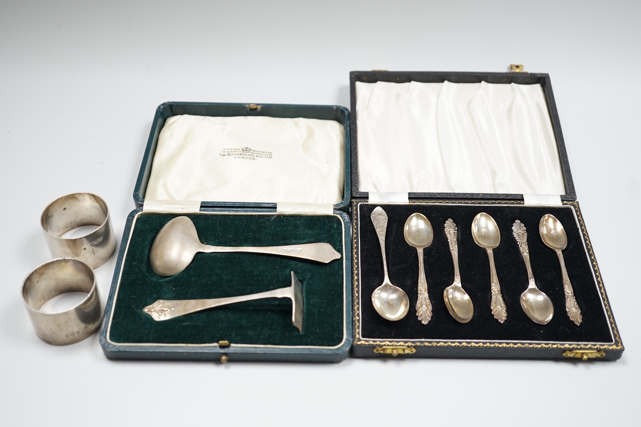 A pair of George V silver napkin rings, Edward Barnard & Sons Ltd, London, 1916 and two cased sets of silver cutlery, coffee spoons and spoon and pusher.